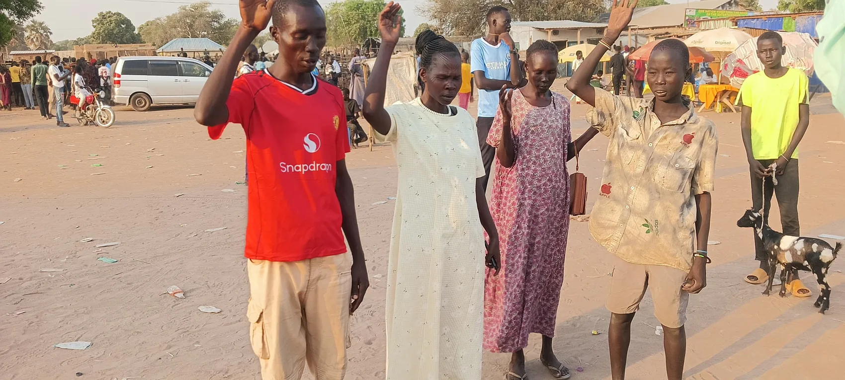 People praying with raised hands at an open-air gathering
